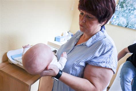 Bild einer Hebamme, die eine junge Mutter zu Hause besucht und das Neugeborene untersucht.