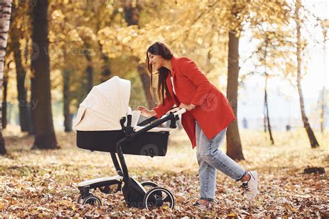 Foto von frischgebackenen Eltern, die mit ihrem Baby im Kinderwagen spazieren gehen