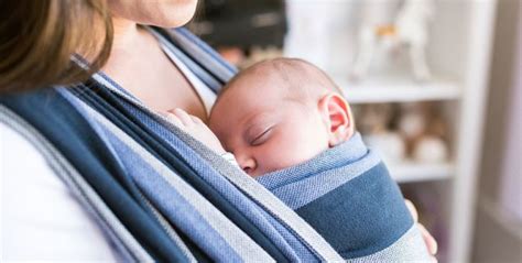 Elternteil, der ein Baby im Tragetuch trägt