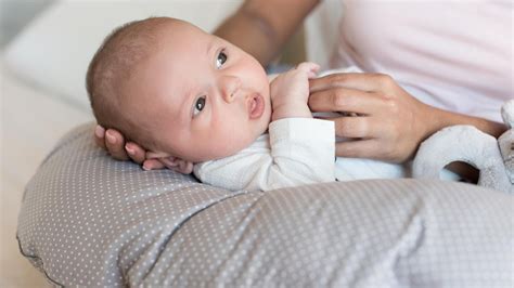Frau mit Baby, die ein Stillkissen benutzt