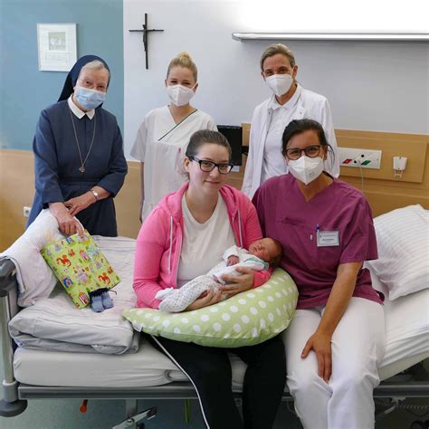 Ein Bild einer Hebamme, die eine frischgebackene Mutter und ihr Baby auf der Wochenbettstation unterstützt.