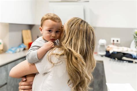 Eine Mutter, die ihr Kleinkind bequem auf einem Hüftsitz trägt, während es neugierig die Umgebung beobachtet.