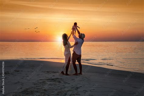 Familie mit Baby am Strand bei Sonnenuntergang