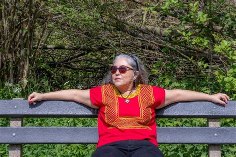 Illustration einer schwangeren Frau, die bequem auf einer Bierbank sitzt, mit Fokus auf die Rocklänge und den Schnitt des Dirndls