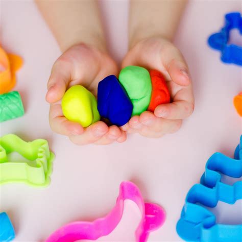 Ein Kind formt mit Knete verschiedene Figuren auf einem Hochstuhltisch