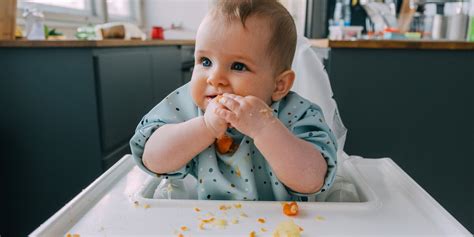 Ein Baby sitzt im Hochstuhl und erkundet eine selbstgemachte Sensorikflasche
