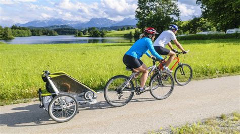 Foto eines Thule Fahrradanhängers mit zwei Kindern, wobei eines in einem Daunensack liegt.