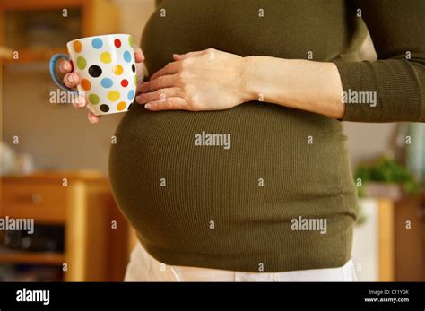 Foto einer schwangeren Frau, die eine Tasse Kräutertee trinkt