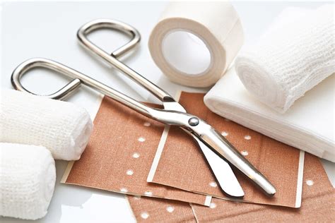 Collage aus verschiedenen Verbandmaterialien: Pflaster, Mullbinden, Dreieckstuch, Verbandsschere und Pinzette.