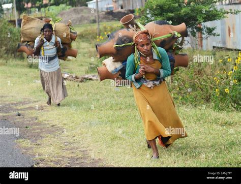 Frauen mit bunten Tragetüchern, die Kinder auf dem Rücken tragen, auf einem afrikanischen Markt.
