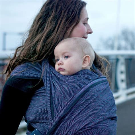 Foto einer Familie, die das Didymos Tragetuch mit dem WELEDA Weiße Malve Fee Muster verwendet.
