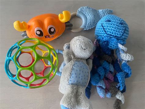 Nahaufnahme der einzelnen Spielzeuge des Oball Aktivitätsbogens: ein bunter Oball, eine kleine Löwenrassel und ein Elefant mit Rassel.