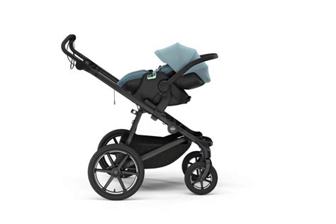 Detailaufnahme, wie ein Adapter an einem Kinderwagengestell befestigt wird und wie die Babyschale darauf einrastet.