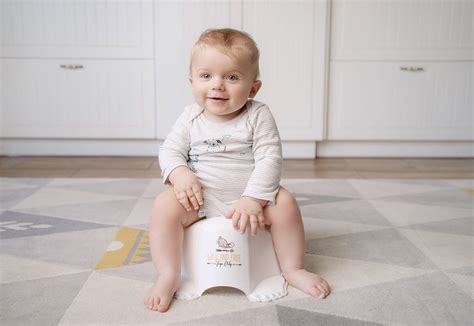 Ein lächelndes Kind sitzt bequem auf einem Tega Baby Töpfchen mit Pfotenmotiv.