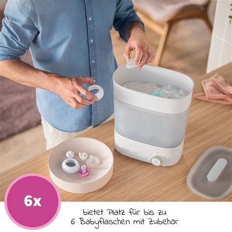 Innenansicht eines elektrischen Dampfsterilisators mit Babyflaschen und Zubehör.