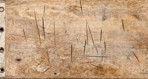 Nahaufnahme von Gebrauchsspuren an einem Holz­hoch­stuhl, wie Kratzer auf der Sitzfläche.