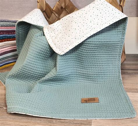 verschiedene Einsatzmöglichkeiten einer Kinderwagendecke: als Kuscheldecke, Spieldecke und Picknickunterlage