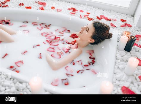 Eine Frau entspannt sich in einer Badewanne mit Kerzen und einem Badeset.