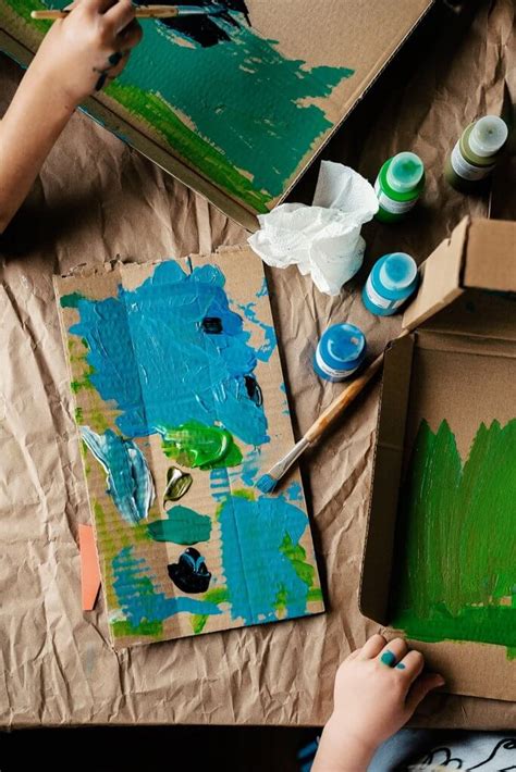 Ein Kind bemalt einen großen Pappkarton, der zu einem Spielhaus umfunktioniert wird.