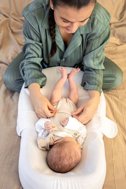 Eine junge Mutter entspannt sich mit einem Stillkissen und einer Kuscheldecke, während ihr Baby friedlich schläft
