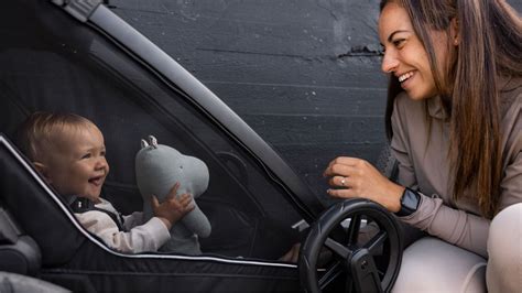 Familie mit einem Thule Chariot Fahrradanhänger, der sowohl als Anhänger als auch als Kinderwagen genutzt wird.