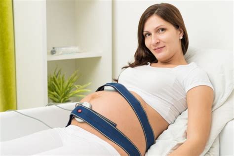 Eine Frau mit CTG-Gurten um den Bauch, die Sensoren sind sichtbar.