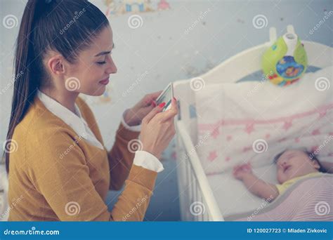 Eine Mutter massiert sanft das Gesicht ihres schlafenden Babys.