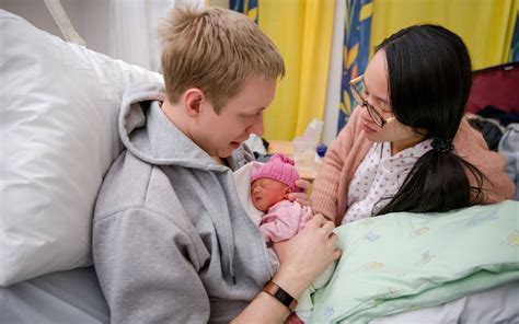 Ehrenamtliche Helferin hält sanft ein Frühchen im Arm.