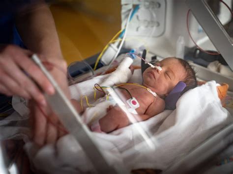Foto einer ehrenamtlichen Baby-Patin, die ein Frühchen liebevoll hält.