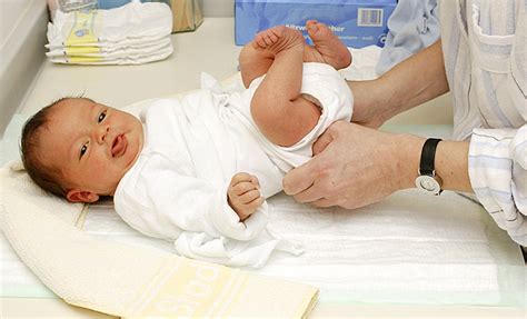 Foto einer Hebamme, die einem Paar das Wickeln eines Babys zeigt