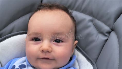 Ein lächelndes Baby, das in die Kamera schaut, mit einem leicht überdurchschnittlich großen Kopf, der aber harmonisch wirkt.