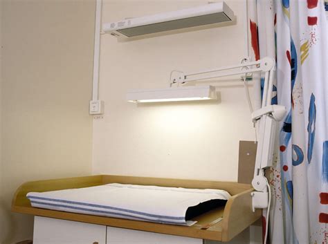 Darstellung eines Babys, das von einem Heizstrahler über dem Wickeltisch gewärmt wird