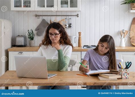 Eine Mutter arbeitet am Laptop, während sie eine freihändige Milchpumpe trägt.
