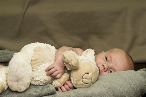 Baby mit Kuscheltier im Bettchen