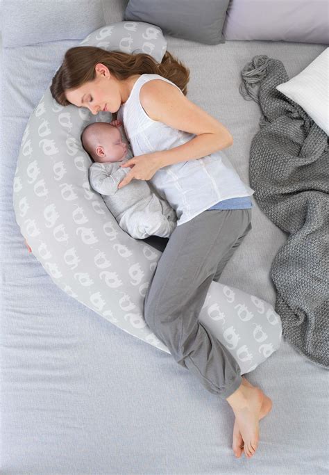 Eine Frau mit Baby auf einem Stillkissen, das ihr Komfort und Unterstützung bietet.