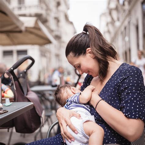 Mutter stillt ihr Baby, Hebamme beobachtet und gibt Ratschläge
