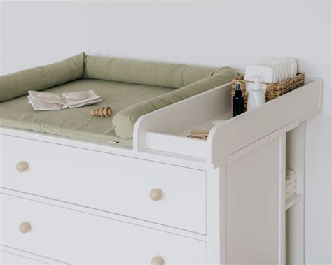 Babyzimmer mit Wickelkommode an einer geraden Wand und einem niedrigen Regal unter der Dachschräge