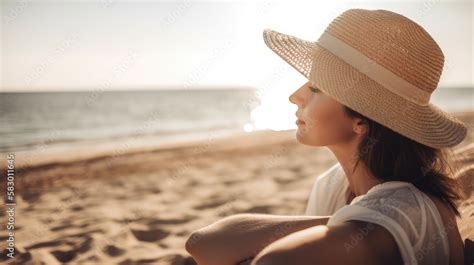 Eine schwangere Frau steht an einem sonnigen Strand und blickt auf das Meer, ihr Babybauch ist deutlich sichtbar.
