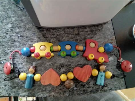 Illustration verschiedener Kinderwagenketten und Hängespielzeuge mit bunten Figuren und Greifelementen.