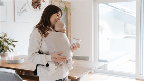Abbildung einer glücklichen Mutter, die ihr Baby in einer ergonomischen Babytrage trägt
