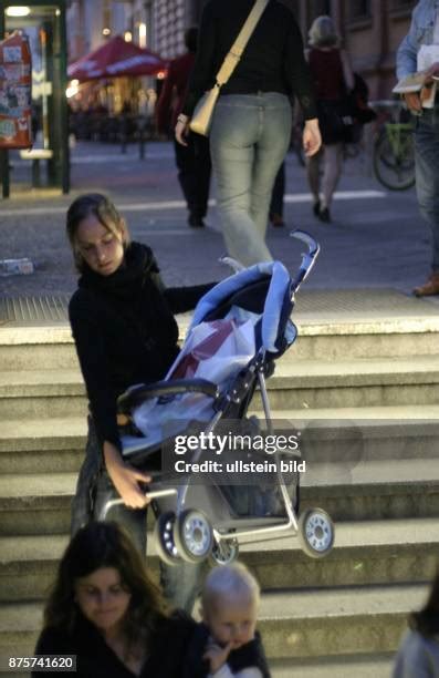 Eine Mutter mit Kinderwagen steht vor einer steilen Treppe am Bahnhof