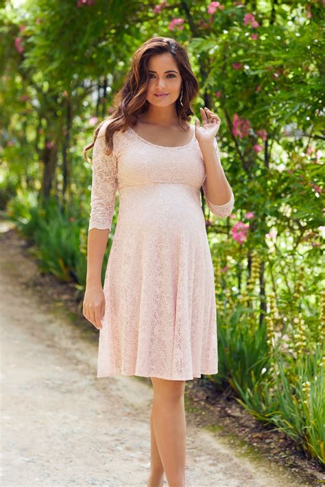 Eine Frau in einem eleganten festlichen Umstandskleid, das ihren Babybauch betont.