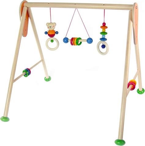 Ein Kind spielt mit einem farbenfrohen Hess Spielbogen mit verschiedenen angehängten Spielzeugen.