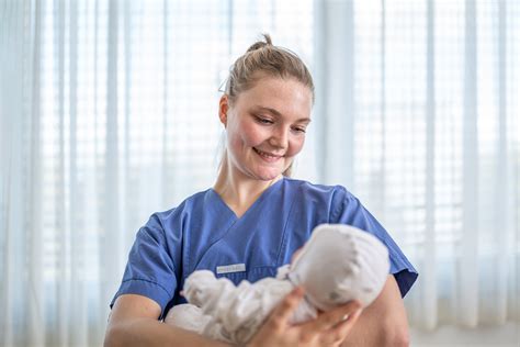 Foto einer Hebamme, die ein Baby in einem Tragetuch hält