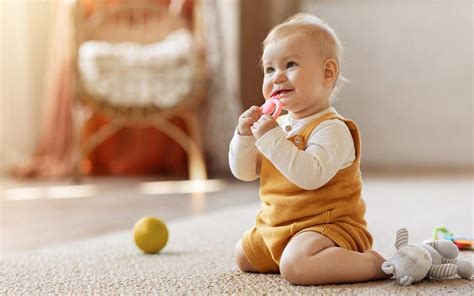 Ein Baby sitzt auf einer Krabbeldecke und schlägt mit einem Holzlöffel auf einen Topf