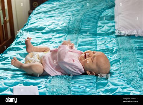 Ein Baby liegt auf einer großen bunten Decke, die von zwei Erwachsenen sanft geschaukelt wird