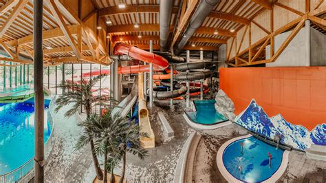 Blick in ein Hallenbad mit Rutschen und einem Spaßbecken