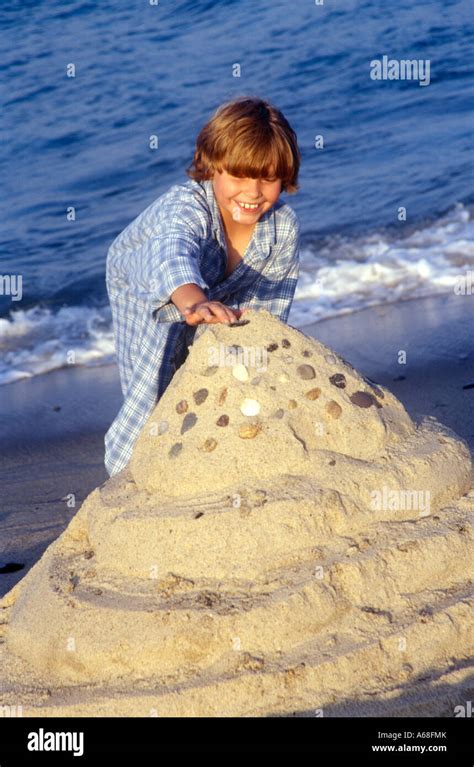 Kinder bauen Sandburgen an einem Seeufer, im Hintergrund Beachvolleyballfeld