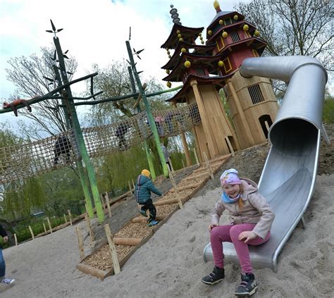 Kinder spielen auf einem modernen Abenteuerspielplatz mit Klettergerüsten und Rutschen