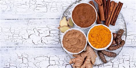 Eine Auswahl an Gewürzen wie Kurkuma und Zimt, sowie eine Tasse Kaffee und ein Glas grüner Tee